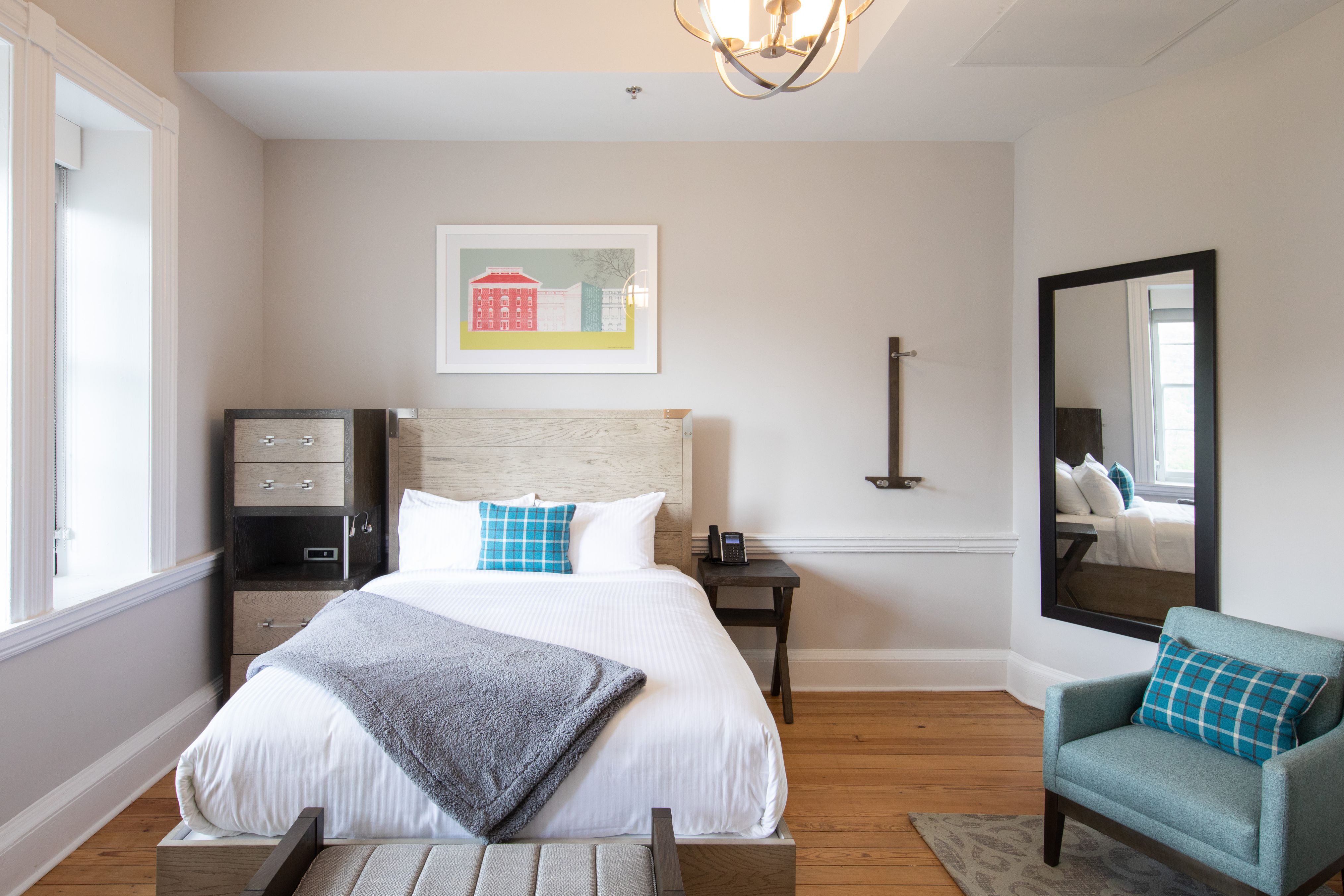 Image of Deluxe Queen Guestroom with Queen-sized bed, accent chair, and wall mirror. The Blackburn Inn & Conference Center, a member of Historic Hotels since 2018, dates to 1828. It is located in Staunton, Virginia.